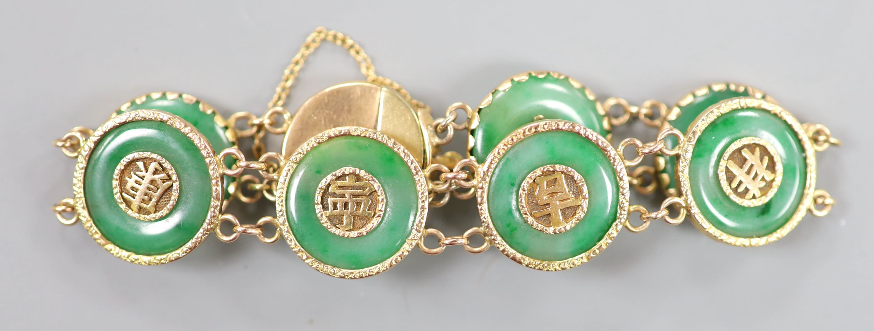 A Chinese yellow metal (stamped 18) and pierced eight stone jade disc set bracelet, with central Chinese characters, 16.5cm approx. gross weight 27.7 grams.